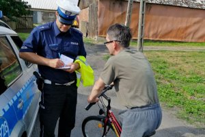 Policjant zapisuje w notatniku dane rowerzysty