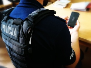 Policjant trzyma w ręku telefon komórkowy