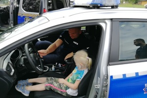 Dziewczynka siedzi na miejscu kierowcy w radiowozie policyjnym
