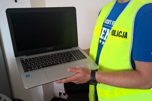 Policjant trzyma w ręku laptopa