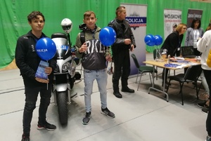 Młodzież pozuje do zdjęcia stojąc przy policyjnym motocyklu
