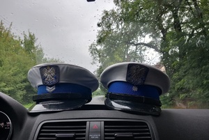 Wnętrze radiowozu z dwiema czapkami policjantów ruchu drogowego