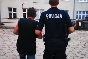 Policjant prowadzi zatrzymanego mężczyznę