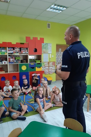 Policjant rozmawia z dziećmi w sali przedszkolnej