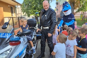 Policjant prezentuje dzieciom służbowy motocykl, na którym siedzi dziewczynka