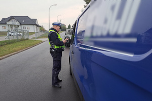 Policjant kontroluje zatrzymanego kierowcę