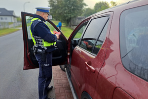 Policjant sprawdza dokumenty zatrzymanego do kontroli kierowcy
