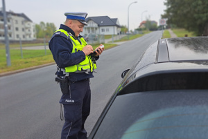 Policjant sprawdza dane kierowcy za pomocą policyjnego urządzenia