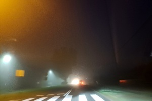 kierowca osobówki przejeżdża przez oświetloną drogę