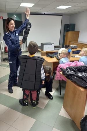 Policjantka opowiada dzieciom o poszczególnych elementach dodatkowego umundurowania policjanów