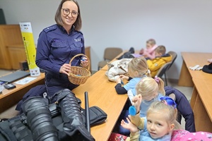 Policjantka trzyma koszyk z odblaskami dla dzieci