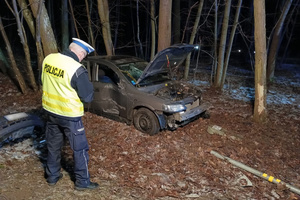 W lesie stoi uszkodzony w skutek kolizji samochód, policjant prowadzi czynności na miejscu