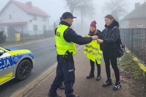 Policjanci drogówki wręczają kamizelki dziewczętom
